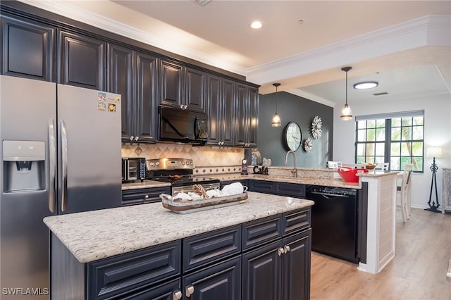 kitchen featuring black appliances, light wood-type flooring, decorative light fixtures, and a center island