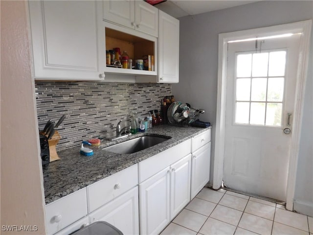 kitchen with light tile patterned flooring, white cabinets, sink, and dark stone counters