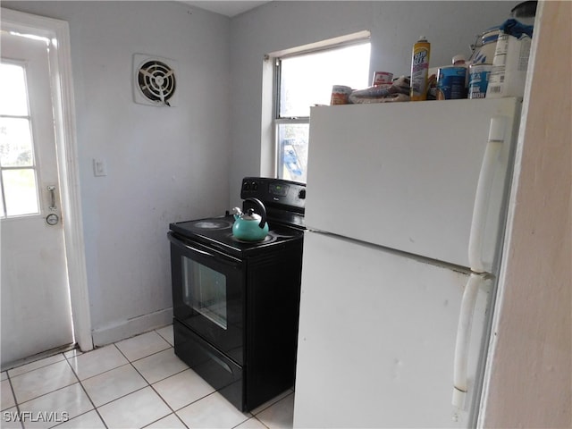 kitchen with black / electric stove, light tile patterned floors, a wealth of natural light, and white refrigerator