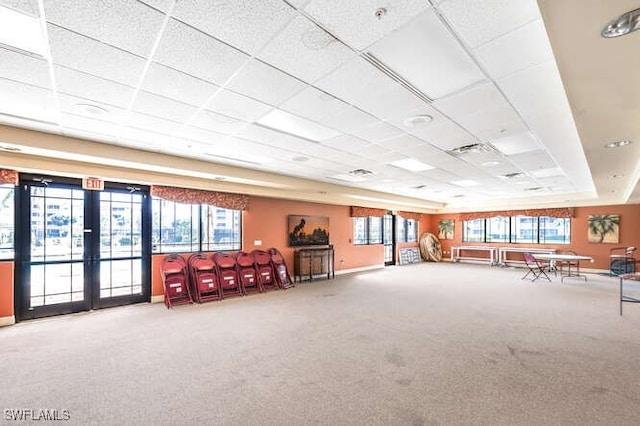 interior space with a wealth of natural light, a drop ceiling, and carpet floors