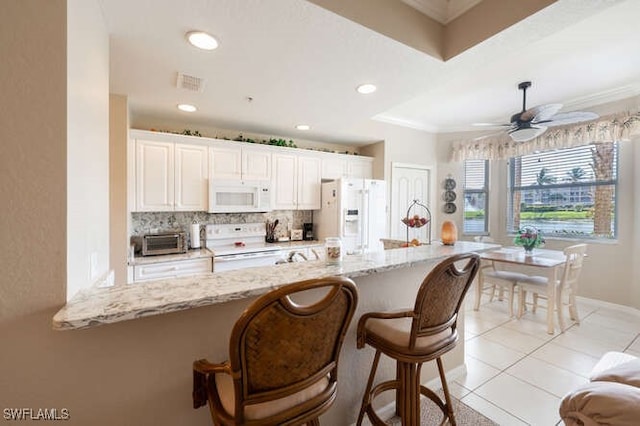 8550 Kingbird Loop Unit 618, Estero, FL 33967 - kitchen with white appliances, decorative backsplash, a breakfast bar area, light stone countertops, and crown molding