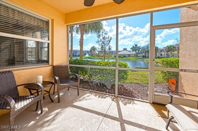 sunroom featuring ceiling fan, a water view, and a wealth of natural light