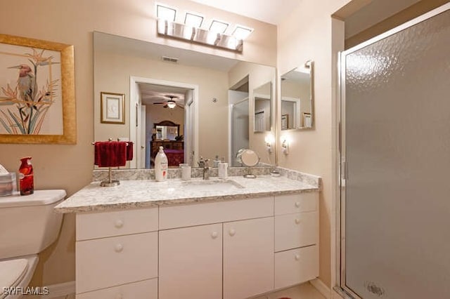 bathroom featuring vanity, toilet, a shower with door, and ceiling fan