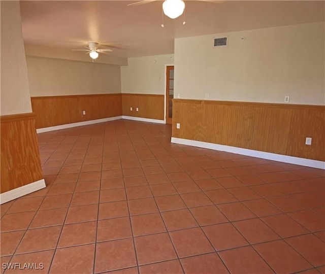 spare room featuring tile patterned flooring, wooden walls, and ceiling fan