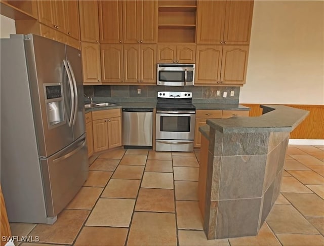 kitchen featuring stainless steel appliances, light tile patterned floors, light brown cabinets, and decorative backsplash