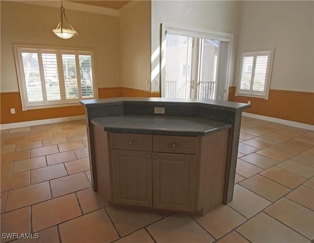 kitchen with hanging light fixtures, light tile patterned flooring, and crown molding