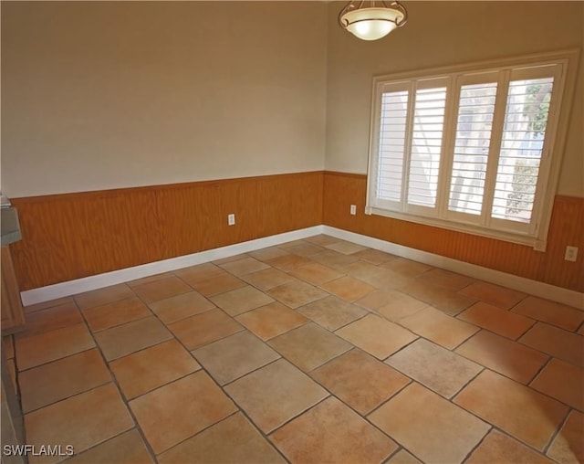 empty room with wooden walls and light tile patterned floors