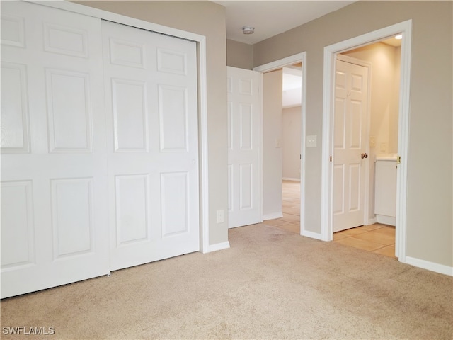 unfurnished bedroom with a closet and light colored carpet