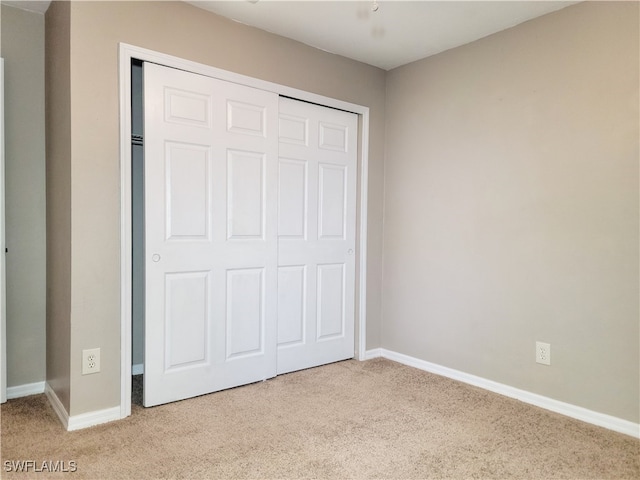 unfurnished bedroom with a closet and light colored carpet