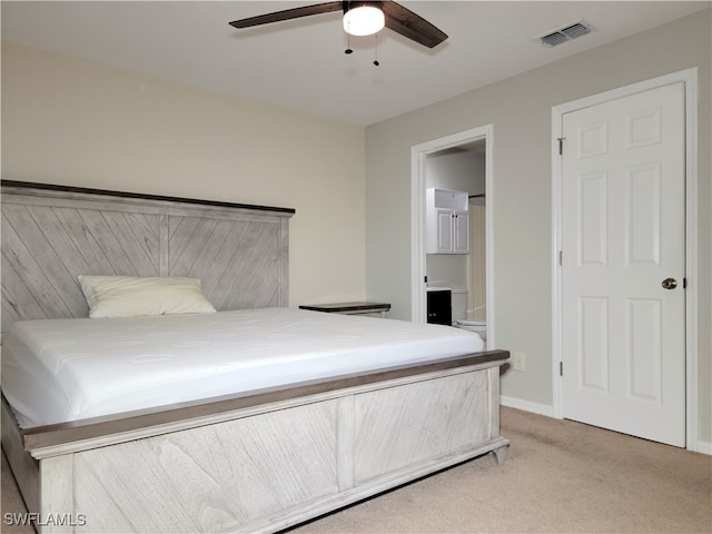 bedroom with light colored carpet, connected bathroom, and ceiling fan