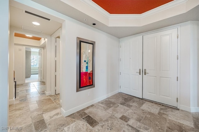 foyer with crown molding and a raised ceiling