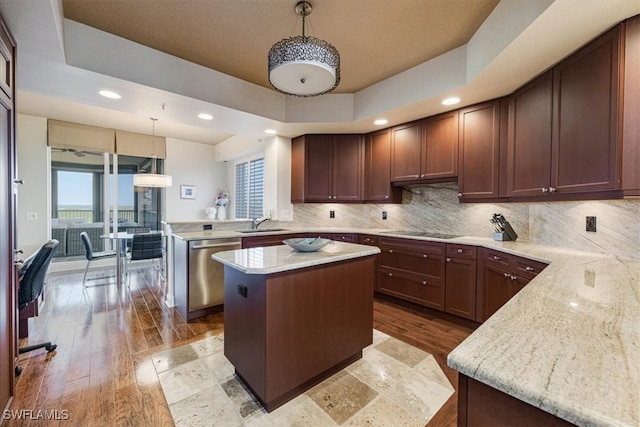 kitchen featuring light hardwood / wood-style flooring, kitchen peninsula, decorative light fixtures, and stainless steel dishwasher