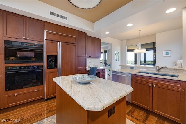 kitchen with hanging light fixtures, light stone counters, dark hardwood / wood-style flooring, double oven, and a center island