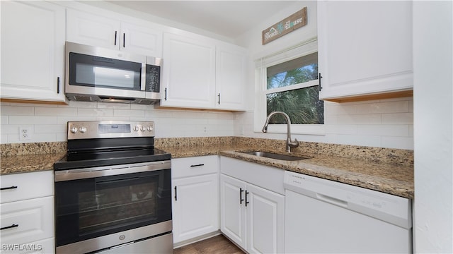 kitchen with sink, white cabinets, dark stone counters, decorative backsplash, and stainless steel appliances