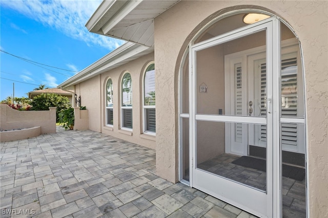 view of exterior entry with a patio area