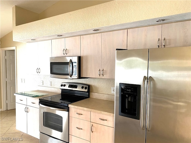 kitchen featuring appliances with stainless steel finishes, lofted ceiling, and light tile patterned floors