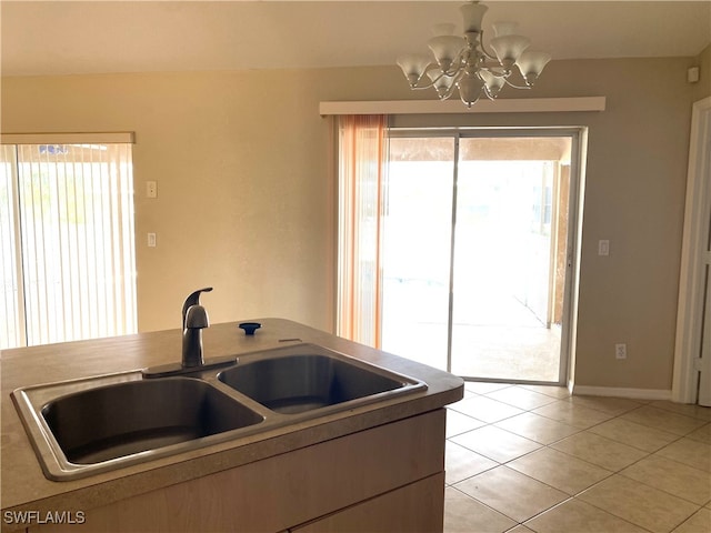 kitchen with light tile patterned floors, a wealth of natural light, sink, and an inviting chandelier