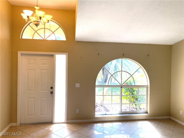 entryway featuring a chandelier, a textured ceiling, and light tile patterned floors