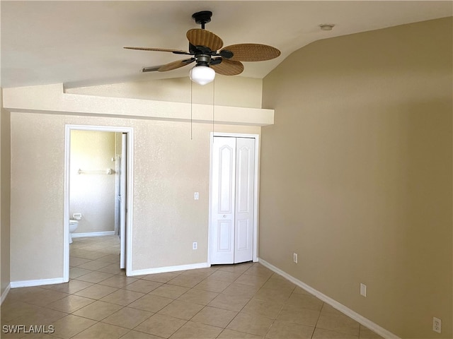 unfurnished bedroom featuring a closet, lofted ceiling, light tile patterned floors, and ceiling fan