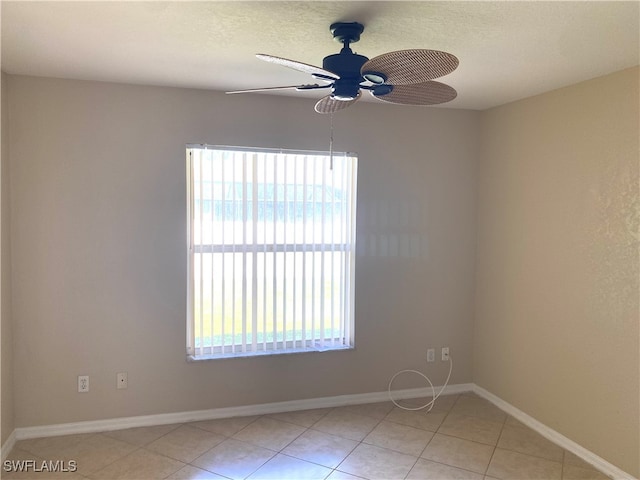 spare room with a healthy amount of sunlight, ceiling fan, and light tile patterned floors