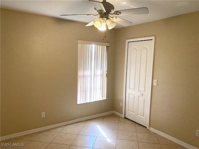 unfurnished bedroom with light tile patterned floors, ceiling fan, and a closet