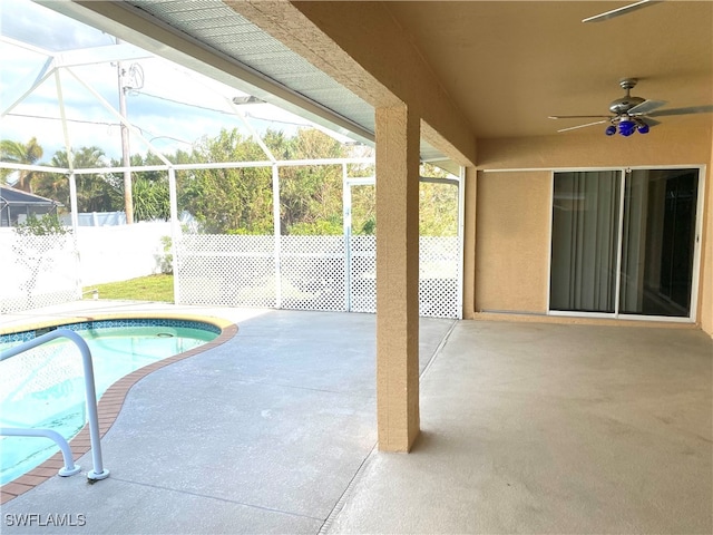 view of pool with ceiling fan, glass enclosure, and a patio area