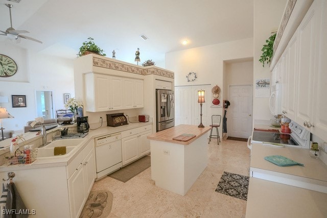 kitchen with white appliances, high vaulted ceiling, sink, kitchen peninsula, and a center island