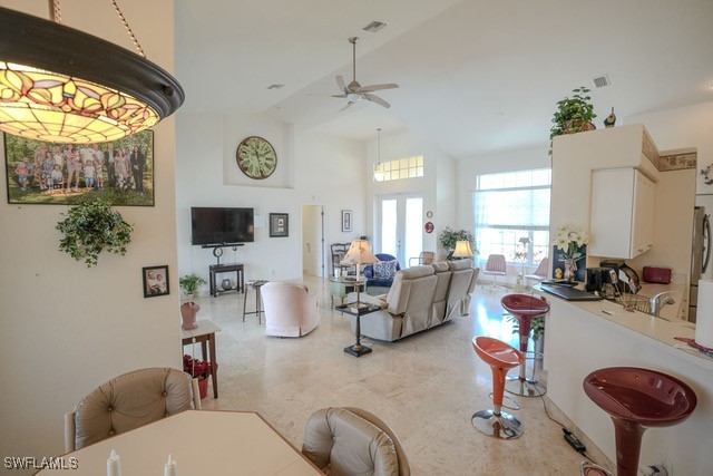 dining area with ceiling fan and high vaulted ceiling