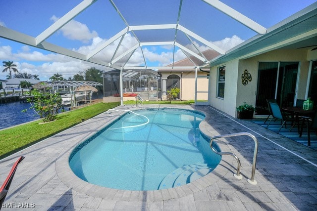 view of pool with a lawn, a water view, glass enclosure, and a patio