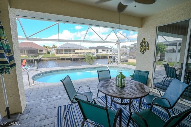 view of pool with a lanai, a water view, and a patio area