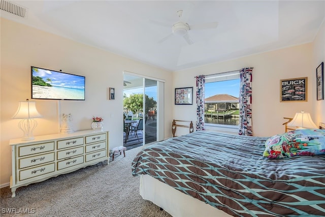 carpeted bedroom with a water view, ceiling fan, and access to exterior