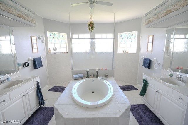 bathroom with vanity, a relaxing tiled tub, tile patterned floors, and ceiling fan