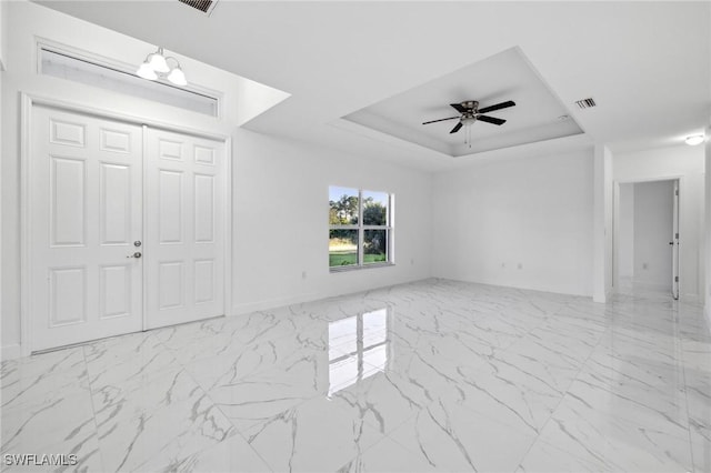 interior space featuring a raised ceiling and ceiling fan