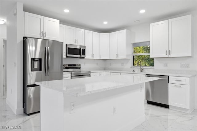 kitchen with a kitchen island, sink, white cabinetry, light stone countertops, and appliances with stainless steel finishes