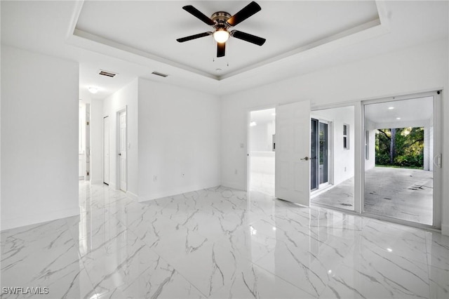 spare room with ceiling fan and a tray ceiling