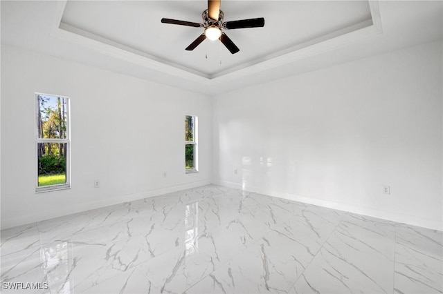 spare room featuring ceiling fan and a raised ceiling