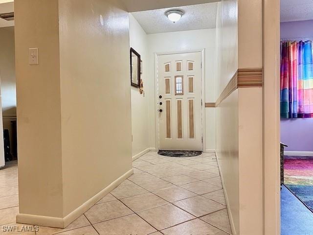 hall featuring light tile patterned flooring and a textured ceiling