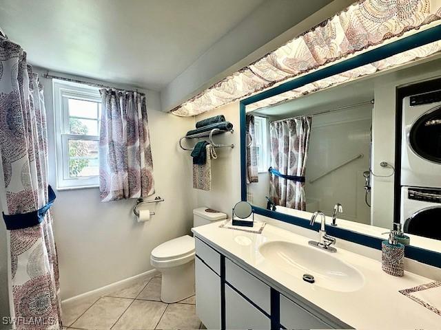 bathroom featuring tile patterned flooring, vanity, toilet, and stacked washer and clothes dryer