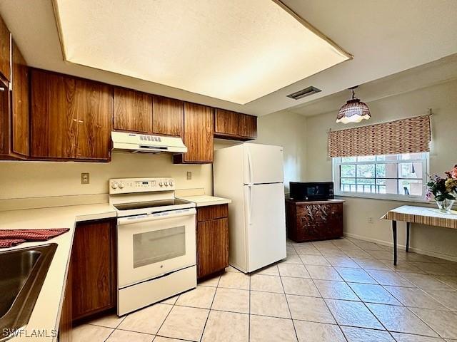 kitchen with sink, light tile patterned floors, pendant lighting, and white appliances