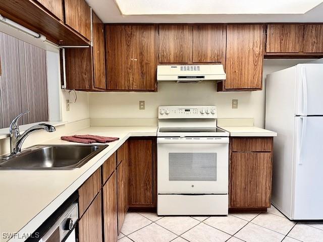 kitchen featuring sink, light tile patterned flooring, and white appliances