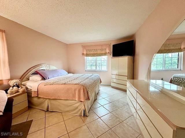 bedroom featuring light tile patterned floors, a textured ceiling, and multiple windows