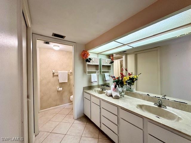 bathroom with toilet, vanity, and tile patterned floors