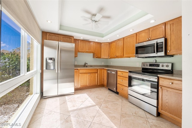 kitchen featuring ceiling fan, light tile patterned flooring, a raised ceiling, and appliances with stainless steel finishes