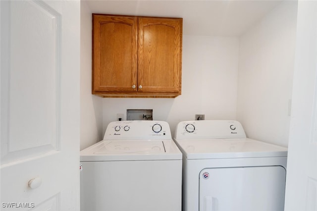 clothes washing area featuring cabinets and separate washer and dryer