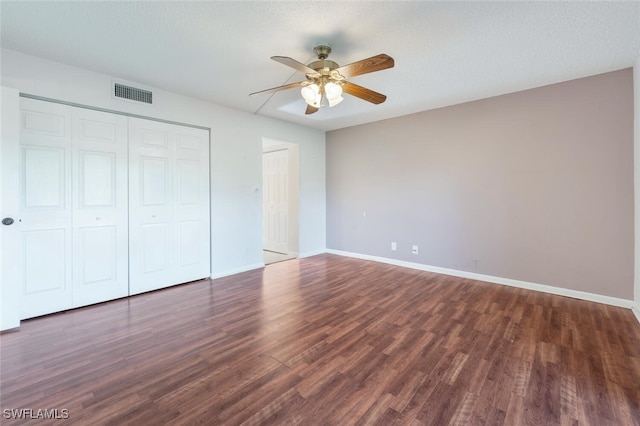 unfurnished bedroom featuring ceiling fan, dark hardwood / wood-style floors, a textured ceiling, and a closet