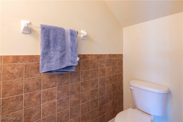 bathroom with tile walls, vaulted ceiling, and toilet