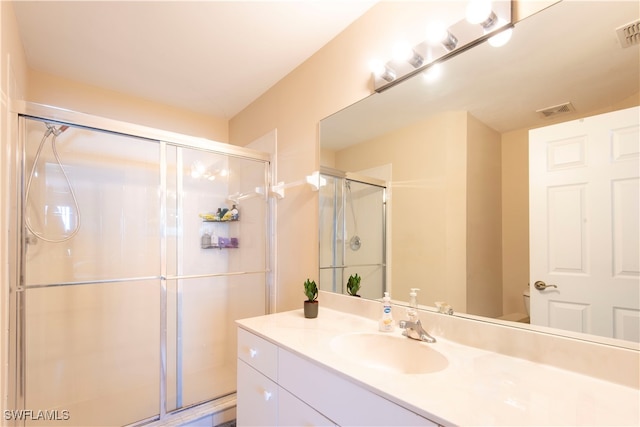 bathroom with a shower with door, vanity, and toilet