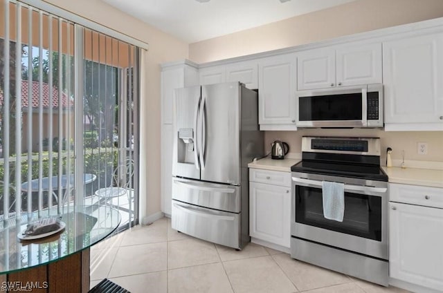 kitchen featuring white cabinets, a wealth of natural light, light tile patterned floors, and appliances with stainless steel finishes