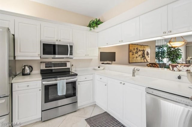 kitchen with appliances with stainless steel finishes, white cabinets, kitchen peninsula, and light tile patterned floors