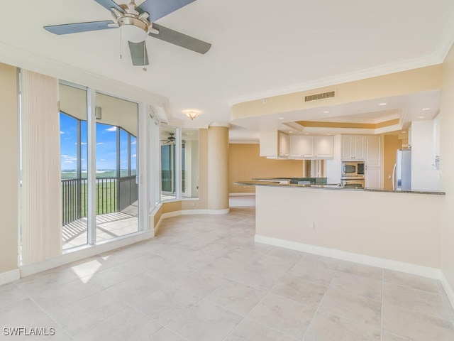 unfurnished living room with a raised ceiling, ceiling fan, light tile patterned floors, and ornamental molding